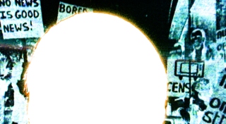 A 16mm film still shows a negative image of a protest. A large white circle or film burn obscures most of the image.