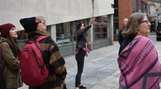 A group of people gather for a tour on a Dublin street on a bright and sunny day.