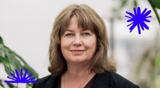 Selina stands facing the camera. She has shoulder length brown hair with a fringe. She wears a black blazer. A blue star and half-star graphic appear in the top right and bottom left of the image.