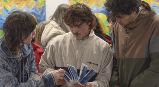 Three people stand looking at a handmade artist book.