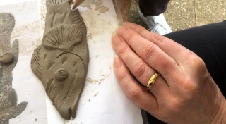 A close up photograph of a person making ceramic fish