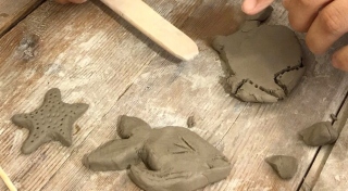 A close up photograph of a person making ceramic fish