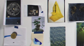 A collection of drawings and research images pinned and taped to the white wall of the artists studio.