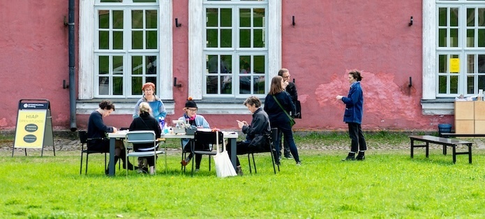 Artists sit at tables outside the Helsinki International Artist Programme's Suomenlinna location